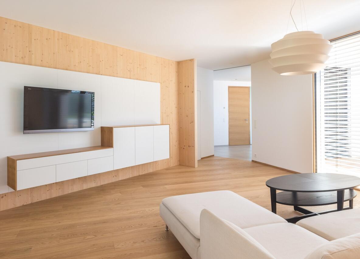 Einfamilienhaus Siegendorf – Innenansicht Wohnzimmer mit Holzboden und moderner Einrichtung, Gollubits Holzbau